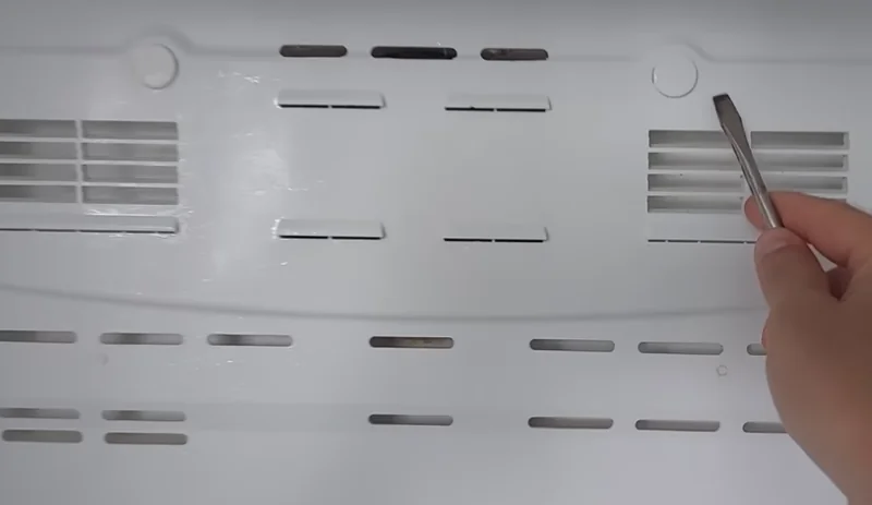 Technician removing a refrigerator vent panel during an in-home appliance repair in Spartanburg SC