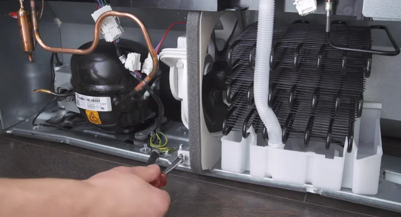 Rear of a refrigerator showing the compressor and dusty condenser coils during a Spartanburg repair visit